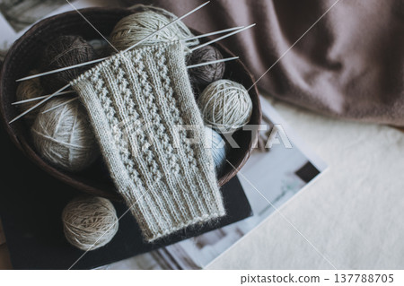Hand knitted socks with needles and yarn ball in a basket. Concept for handmade and hygge slow life. Hand knitted socks with needles and yarn ball in a basket. Concept for handmade and hygge slow life. 137788705