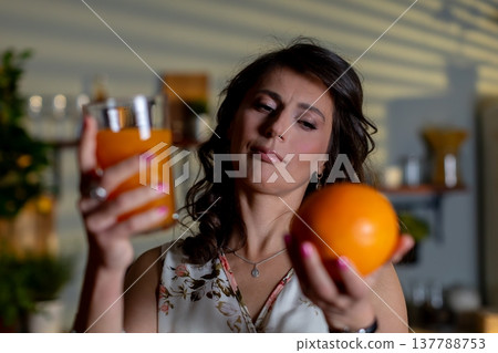 Woman inspects beverage, Woman evaluates drink quality accurately, Individual carefully checks freshness of juice, Person assesses quality and freshness of beverage at home Woman inspects beverage, Woman evaluates drink quality accurately, Individual carefully checks freshness of juice, Person assesses quality and freshness of beverage at home 137788753