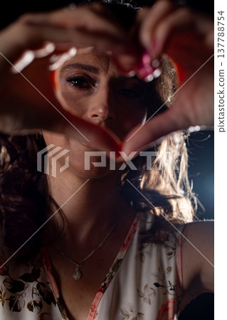 Lowangle woman framing heart symbol, playful expression, rim backlight and sparkling makeup, warm night vibe, shallow focus with grainy film mood, energetic celebratory scene Lowangle woman framing heart symbol, playful expression, rim backlight and sparkling makeup, warm night vibe, shallow focus with grainy film mood, energetic celebratory scene 137788754