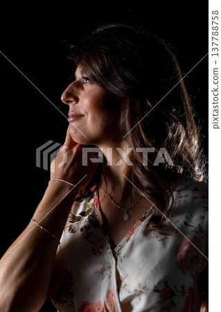 Woman planning carefully, Thoughtful female silhouette contemplating with quiet purpose, Woman in dim lighting carefully strategizing her next move with intent focus 137788758
