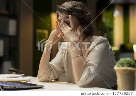 Drained restless woman going into mental haze with after hours tasks, rubbing eyes and struggling to stay awake. Employee with intense workload and discomfort feels anxious and overwhelmed. Drained restless woman going into mental haze with after hours tasks, rubbing eyes and struggling to stay awake. Employee with intense workload and discomfort feels anxious and overwhelmed. 137789297