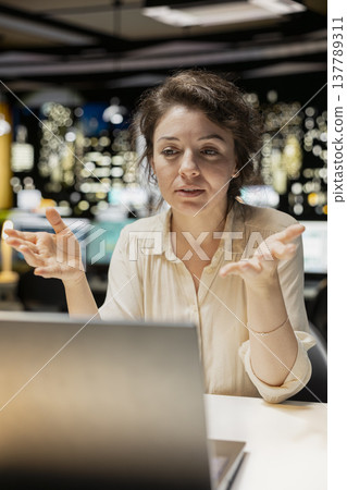 Woman joining a remote webinar from desk using laptop and headset, interacting with participants. Person maintaining eye contact, exchanging ideas in a chat that promotes networking. Woman joining a remote webinar from desk using laptop and headset, interacting with participants. Person maintaining eye contact, exchanging ideas in a chat that promotes networking. 137789311
