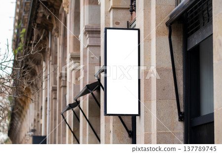 Blank vertical signage mockup displaying on a stone building facade, creating an outdoor advertising design template for storefront promotion and business branding Blank vertical signage mockup displaying on a stone building facade, creating an outdoor advertising design template for storefront promotion and business branding 137789745