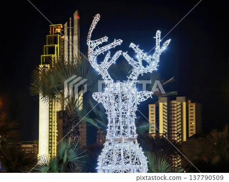Vividly Lit Reindeer Statue Creates Festive Charm Against Urban Skyline And Colorful Signage Vividly Lit Reindeer Statue Creates Festive Charm Against Urban Skyline And Colorful Signage 137790509