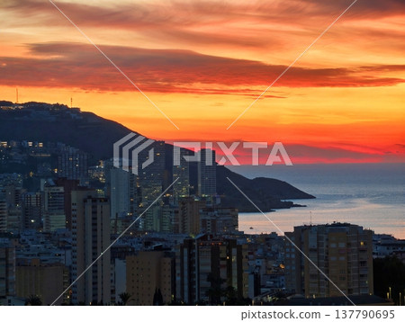 Sunset Over Illuminated Cityscape, Dusk Settles Over Glowing Buildings And Distant Sea Horizon Sunset Over Illuminated Cityscape, Dusk Settles Over Glowing Buildings And Distant Sea Horizon 137790695