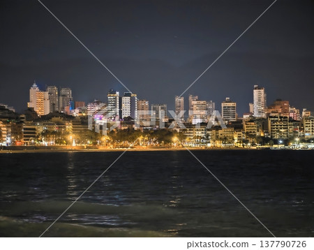 Bright Cityscape Over Water, Vivid Nighttime City View With Shimmering Water And Tall Buildings Bright Cityscape Over Water, Vivid Nighttime City View With Shimmering Water And Tall Buildings 137790726