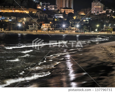 Coastal Night Scene, Shining Shoreline With City Lights, Reflective Waves Illuminate Nighttime Waterfront Coastal Night Scene, Shining Shoreline With City Lights, Reflective Waves Illuminate Nighttime Waterfront 137790731