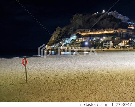 Lone Safety Buoy Placed On Abandoned Seaside With Distant Illumination And Calm Surroundings Lone Safety Buoy Placed On Abandoned Seaside With Distant Illumination And Calm Surroundings 137790747