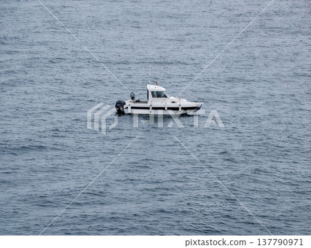 Silent White Boat Amidst Tranquil Blue Waters, Isolated Vessel On Sea Under Overcast Skies Conveying Solitude 137790971