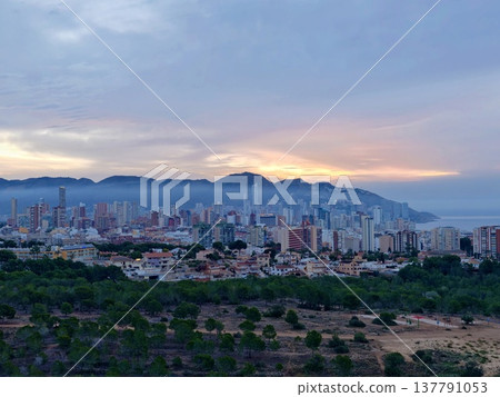 Urban Skyline Vista, Vivid Urban Horizon Featuring Mountain Backdrop And Layered Cloud Formations 137791053