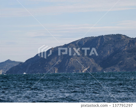 Dramatic Coastal Landscape Scene, Rugged Hillside Emerging From Frothy Water With Textured Cliffs Dramatic Coastal Landscape Scene, Rugged Hillside Emerging From Frothy Water With Textured Cliffs 137791297