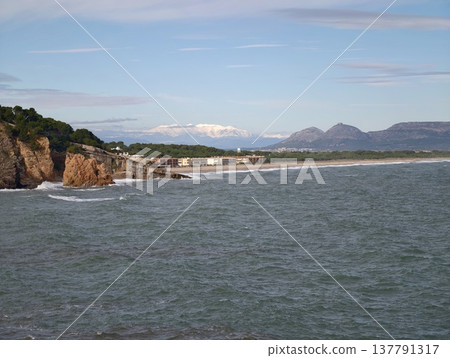 Tranquil Headland Gazing Over Calm Ocean, Scenic Coastal Panorama With Cliffs And Distant Mountains Tranquil Headland Gazing Over Calm Ocean, Scenic Coastal Panorama With Cliffs And Distant Mountains 137791317
