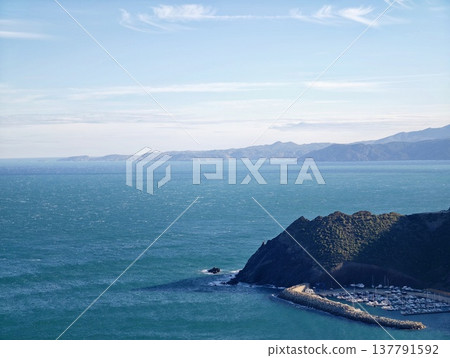 Seaside Promontory Embracing Wide Ocean, Cliff Protrudes Into Immense Azure Sea Beneath Open Skies Seaside Promontory Embracing Wide Ocean, Cliff Protrudes Into Immense Azure Sea Beneath Open Skies 137791592