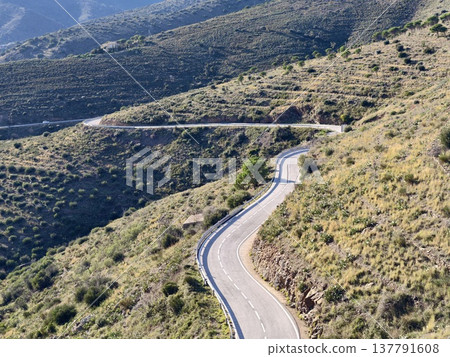 Winding Highway Amid Sunlit Hills, Sunlit Hilly Landscape With Twisting Road And Distant Ridges Winding Highway Amid Sunlit Hills, Sunlit Hilly Landscape With Twisting Road And Distant Ridges 137791608