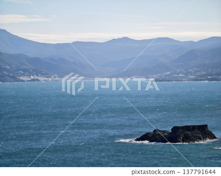 Rugged Island With Harbor View, Secluded Rocky Island With Distant Harbor And Mountain Slopes 137791644