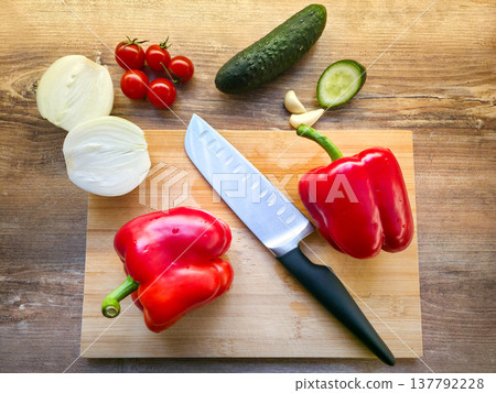 Fresh vegetables: peppers, cucumbers, onions, tomatoes, and garlic on a cutting board with a knife. Healthy dietary nutrition. Consumption of vegetables in the diet. High quality photo Fresh vegetables: peppers, cucumbers, onions, tomatoes, and garlic on a cutting board with a knife. Healthy dietary nutrition. Consumption of vegetables in the diet. High quality photo 137792228