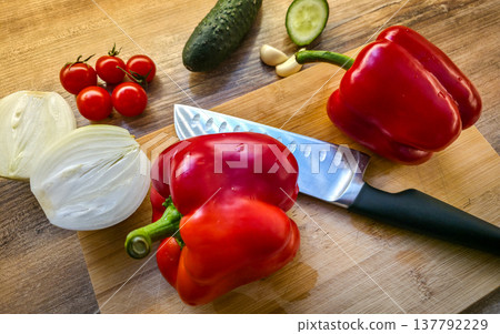 Fresh vegetables: peppers, cucumbers, onions, tomatoes, and garlic on a cutting board with a knife. Healthy dietary nutrition. Consumption of vegetables in the diet. High quality photo Fresh vegetables: peppers, cucumbers, onions, tomatoes, and garlic on a cutting board with a knife. Healthy dietary nutrition. Consumption of vegetables in the diet. High quality photo 137792229