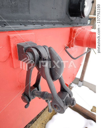 A close-up of the screw coupling of a red vintage locomotive 137792280