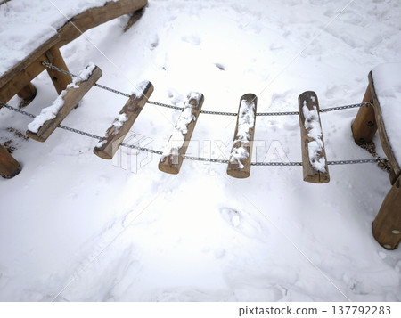Children's rope bridge made from a log under the snow 137792283