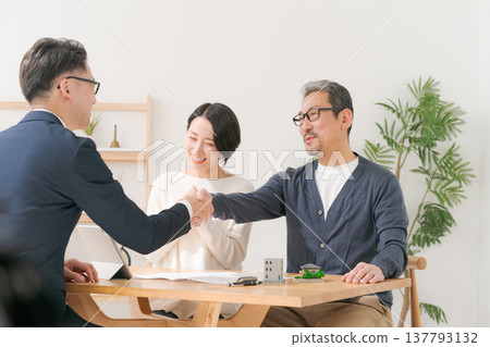A middle-aged couple shakes hands with a salesman. A middle-aged couple shakes hands with a salesman. 137793132