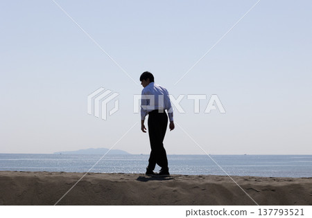 Silhouette of a man standing on the sand 137793521