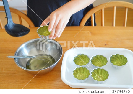 在家製作果凍的場景。特寫鏡頭拍攝了雙手將果凍混合物從碗倒入模具的畫面。 137794250