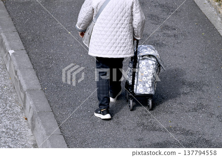 在日本橫濱，一位戴著口罩的老婦人坐在手推車上，由於手推車顛簸過路面，她行走十分困難……人生究竟是什麼？ 137794558