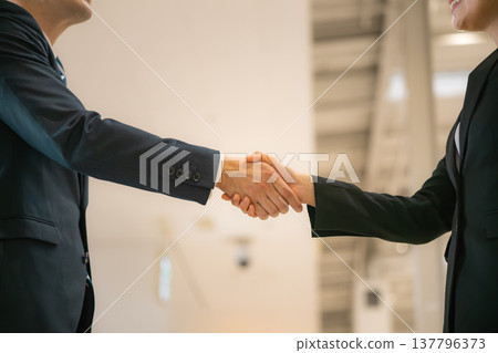 A businessman and a woman shake hands. ■Photography assistance provided by: Kansai International Airport (KIX) 137796373