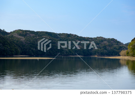 寧靜的湖畔景色,開闊的湖岸線在藍天下綿延展開。 寧靜的湖畔景色,開闊的湖岸線在藍天下綿延展開。 137798375