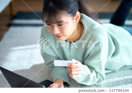 Close-up of a woman entering credit card information while looking at a computer screen. Close-up of a woman entering credit card information while looking at a computer screen. 137799104