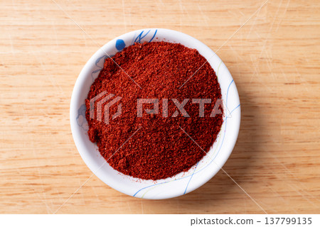 Red chili pepper powder in a bowl on wooden background, Table top view Red chili pepper powder in a bowl on wooden background, Table top view 137799135