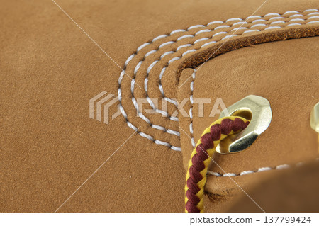 Close-up detail of tan nubuck leather boot with white stitching and braided lace 137799424