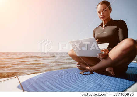 Woman Laptop Ocean - Working on laptop while sitting on a boat on a sunny day. Woman Laptop Ocean - Working on laptop while sitting on a boat on a sunny day. 137800980