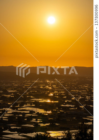 [A magnificent view in early summer] Sunset in the Tonami Plain and scattered villages in early summer and reflections in the rice fields [Toyama Prefecture] 137800996