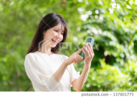 A woman with a smartphone, fresh green A woman with a smartphone, fresh green 137801775