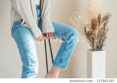 A woman wearing denim jeans sitting in a chair 137802165