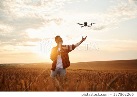 Using drone, controlling it. Male farmer is on the wheat agricultural field Using drone, controlling it. Male farmer is on the wheat agricultural field 137802266