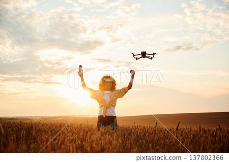With drone that is flying. Beautiful woman is on the wheat agricultural field 137802366