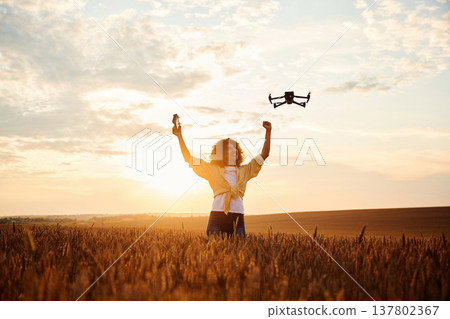 With drone that is flying. Beautiful woman is on the wheat agricultural field 137802367