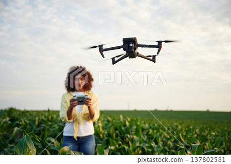 Little help from a drone, controlling it. Woman is on the corn agricultural field 137802581