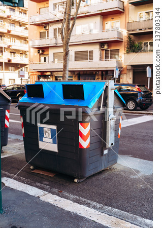 Large waste container on the street with buildings in the background during daylight Large waste container on the street with buildings in the background during daylight 137803144