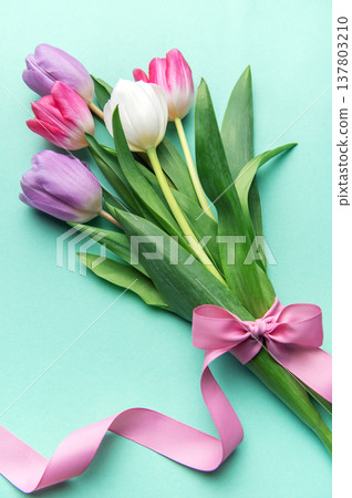 Tulips bouquet with pink ribbon on mint background Tulips bouquet with pink ribbon on mint background 137803210