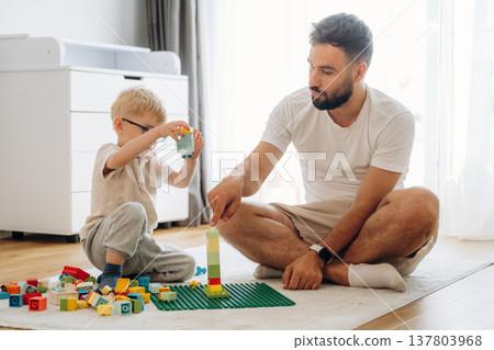 Parenting conception. Father is playing in the room with his little son with construction sets 137803968