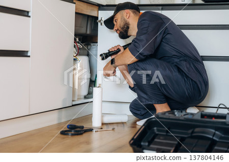 Plumber working in the kitchen under the sink 137804146