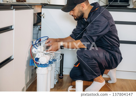 Brand new filters. Plumber working in the kitchen under the sink 137804147