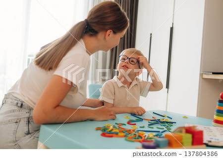 Doctor is teaching the kid. Speech therapist is with young boy indoors Doctor is teaching the kid. Speech therapist is with young boy indoors 137804386