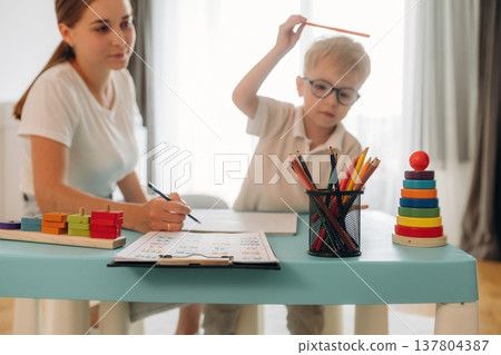 Doctor is teaching the kid. Speech therapist is with young boy indoors 137804387