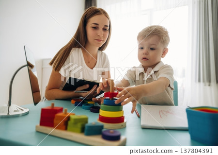 Playing with toys, motor skills. Speech therapist is with young boy indoors 137804391