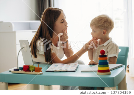 Notepad with alphabet. Speech therapist is with young boy indoors 137804399