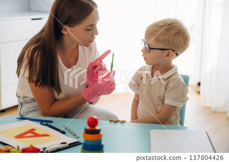 Special tests for tongue by using device. Speech therapist is with young boy indoors 137804426